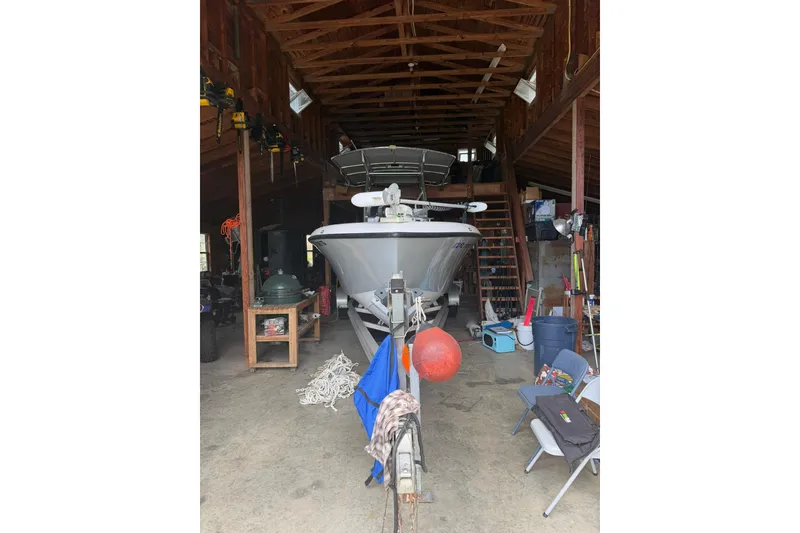 Slide: The Image of 2022 Bluewater 2550 CC boat stored in a wooden garage with various equipment. - 3