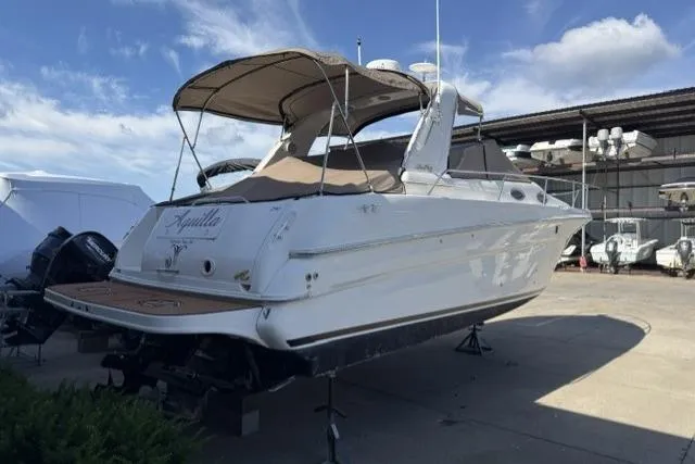 The Image of 1999 Sea Ray 290 Sundancer boat on dry dock, featuring a sleek white exterior. - 0