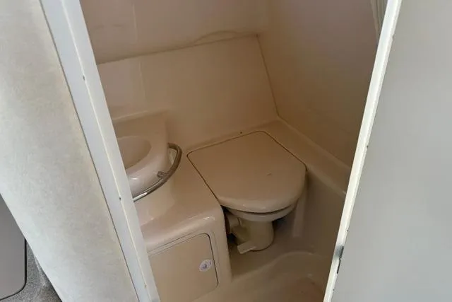 Slide: The Image of 1999 Sea Ray 290 Sundancer boat bathroom with compact toilet and sink. - 13