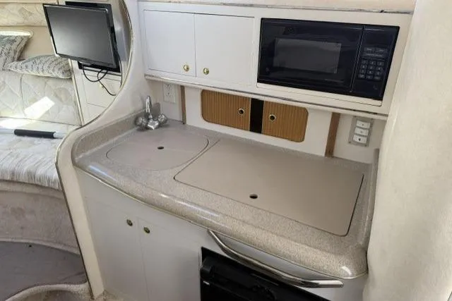 Slide: The Image of Interior of 1999 Sea Ray 290 Sundancer with kitchenette, featuring sink and microwave. - 14