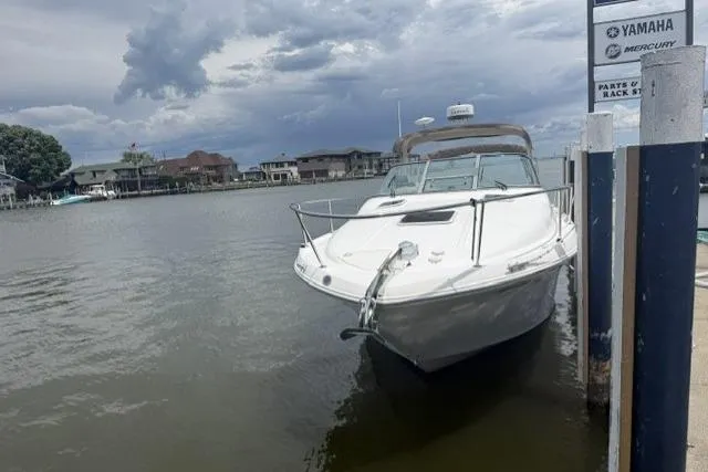 Slide: The Image of 1999 Sea Ray 290 Sundancer docked by waterfront homes under cloudy skies. - 18