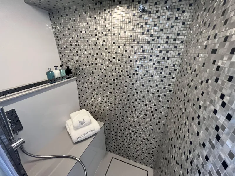 Slide: The Image of A modern bathroom with mosaic tiles and towels on a shelf. - 12