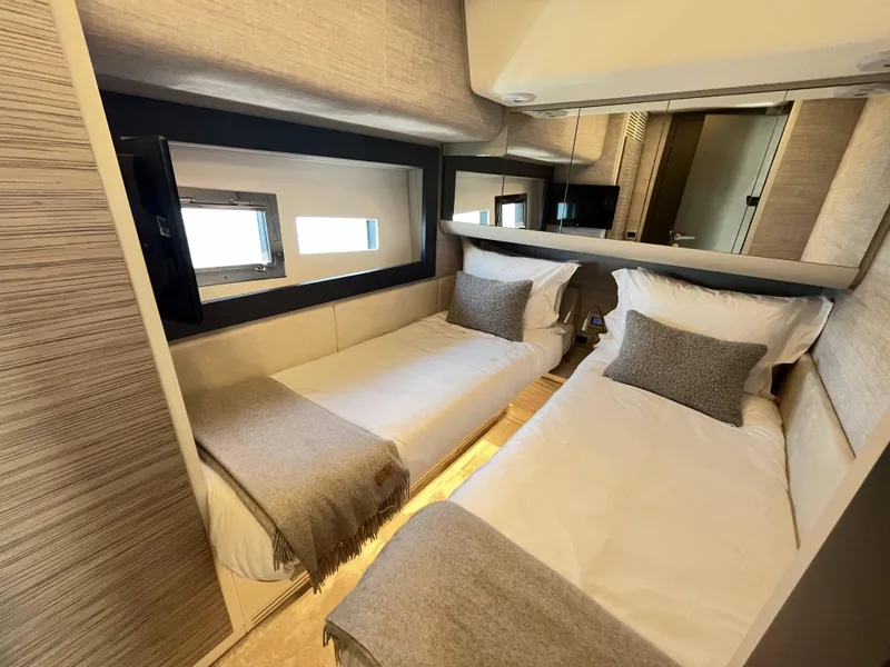 Slide: The Image of Two single beds in a sleek cabin with windows and mirrors. - 16