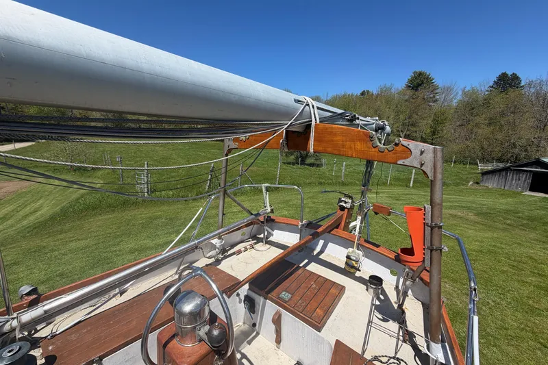 Slide: The Image of 1991 Hylan Offshore Steel Cutter sailboat deck with mast and rigging, set against a grassy landscape. - 24
