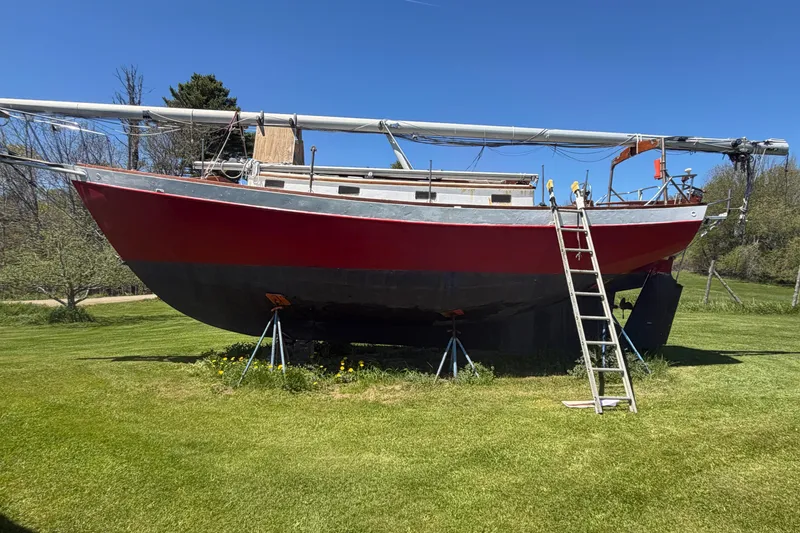 Slide: The Image of Red 1991 Hylan Offshore Steel Cutter sailboat on grass with ladder and clear sky. - 29