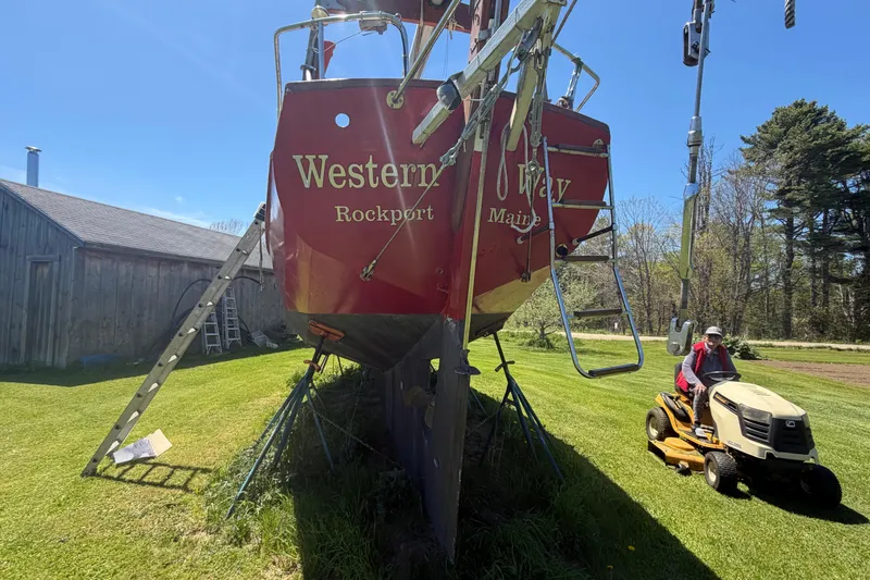 Slide: The Image of Red Hylan Offshore Steel Cutter boat on lawn, 1991 model, with person on lawnmower nearby. - 30