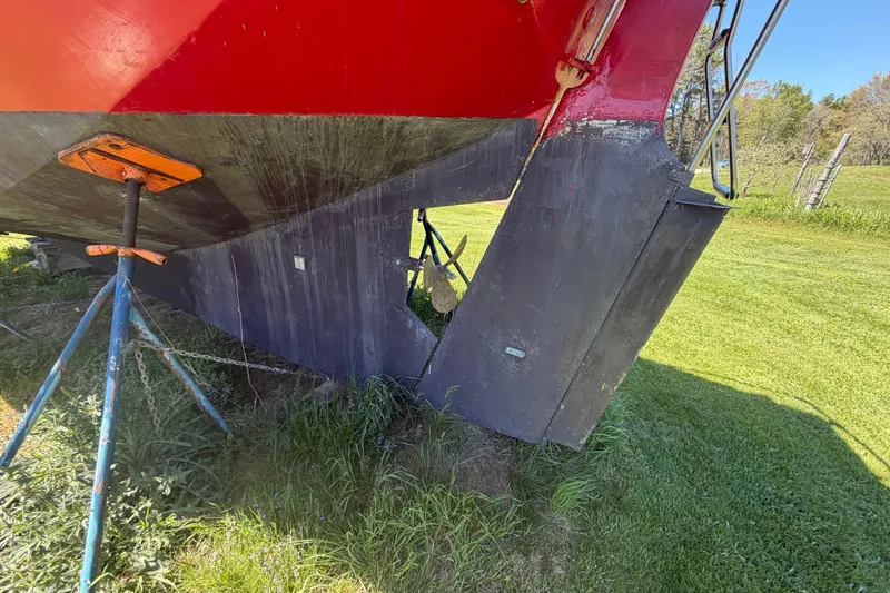 Slide: The Image of 1991 Hylan Offshore Steel Cutter on stands, showing hull and rudder in grassy area. - 31