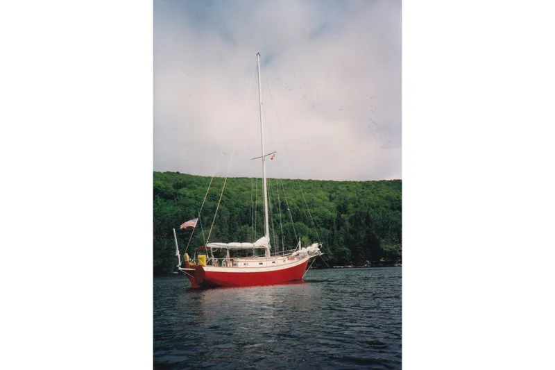 Slide: The Image of Red 1991 Hylan Offshore Steel Cutter sailboat on a calm lake with forested hills. - 33