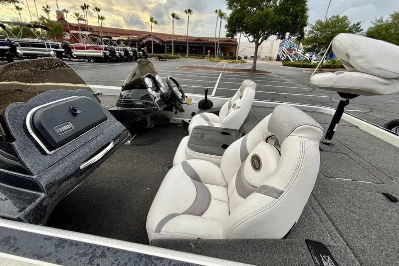 Slide: The Image of 2006 Champion 198 Elite boat interior with white seats and dashboard in a parking lot. - 10