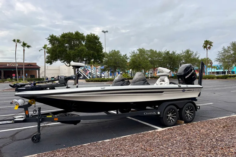 Slide: The Image of 2006 Champion 198 Elite boat on trailer in parking lot with trees and buildings. - 4