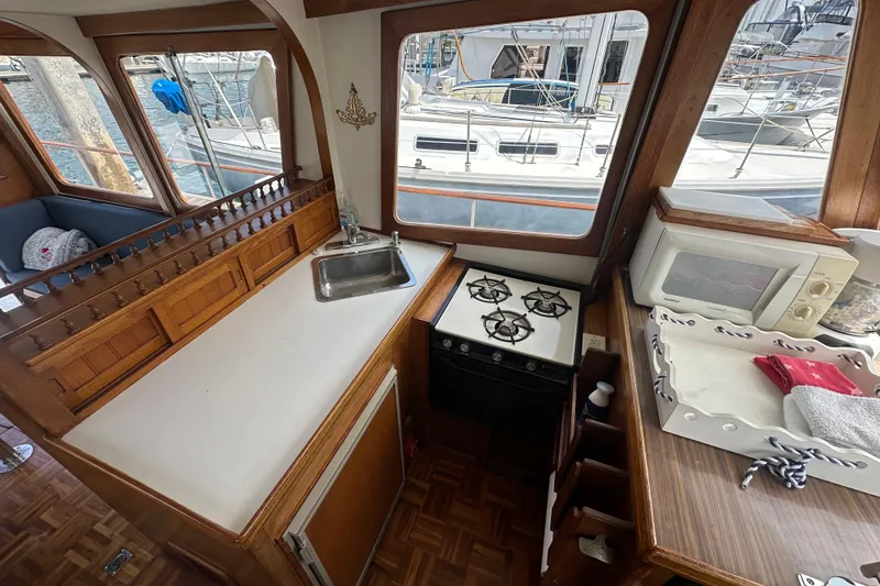Slide: The Image of 1973 CHB 33 boat interior with kitchen, stove, sink, and microwave, docked at marina. - 17