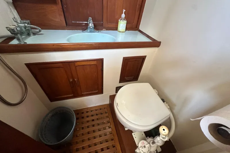 Slide: The Image of 1973 CHB 33 boat bathroom with wooden cabinets, sink, and marine toilet. - 27