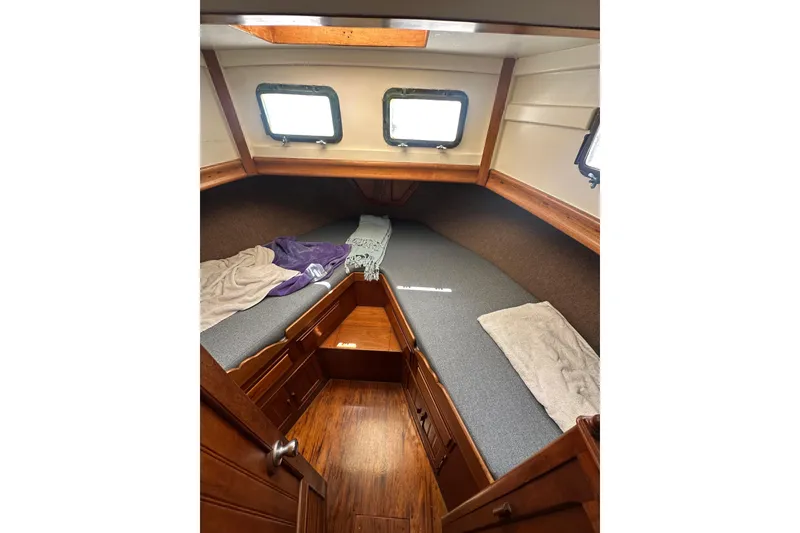 Slide: The Image of Cozy cabin interior of a 1973 CHB 33 boat with wooden accents and twin windows. - 28