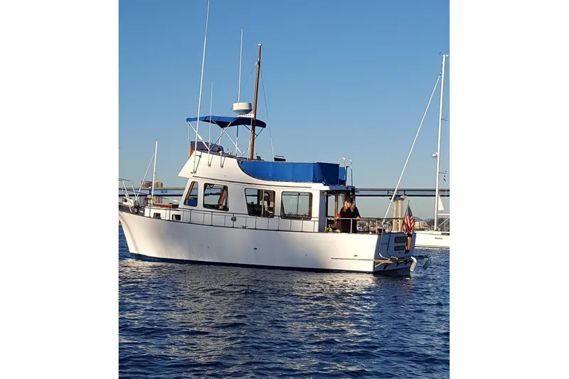 Slide: The Image of 1973 CHB 33 boat on water, featuring blue canopy and American flag. - 33