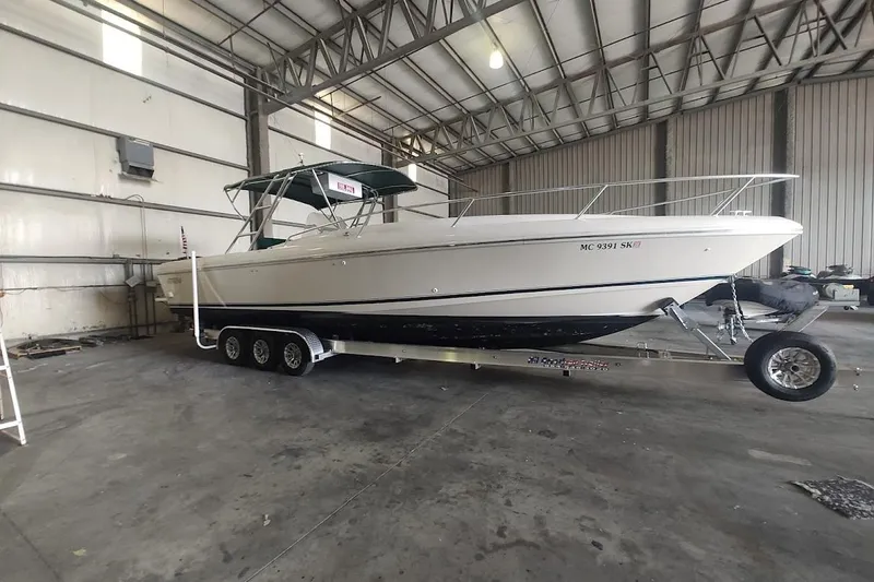 The Image of 1994 Intrepid 322 Cuddy boat on trailer in spacious indoor storage facility. - 0