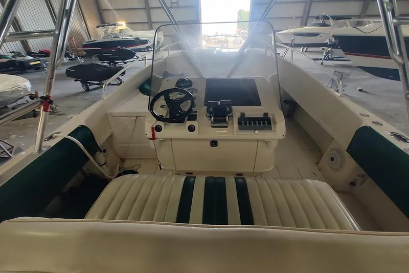 Slide: The Image of 1994 Intrepid 322 Cuddy boat interior with steering wheel and control panel in a storage facility. - 13