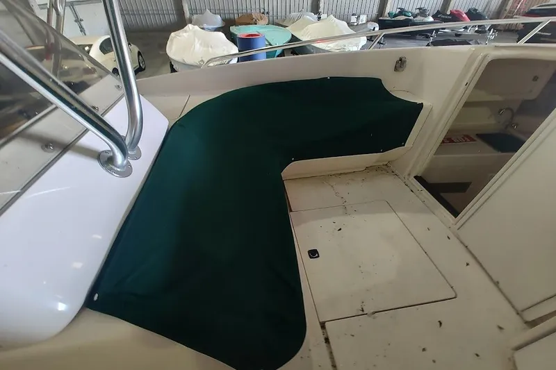 Slide: The Image of 1994 Intrepid 322 Cuddy boat interior with green cover, showing seating and storage area. - 14