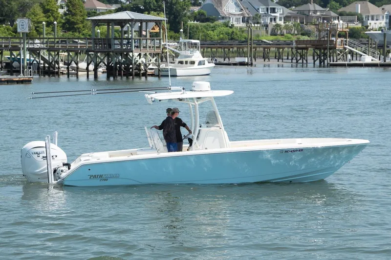 Slide: The Image of 2024 Pathfinder 2700 Open boat cruising on a scenic waterfront with houses in the background. - 2