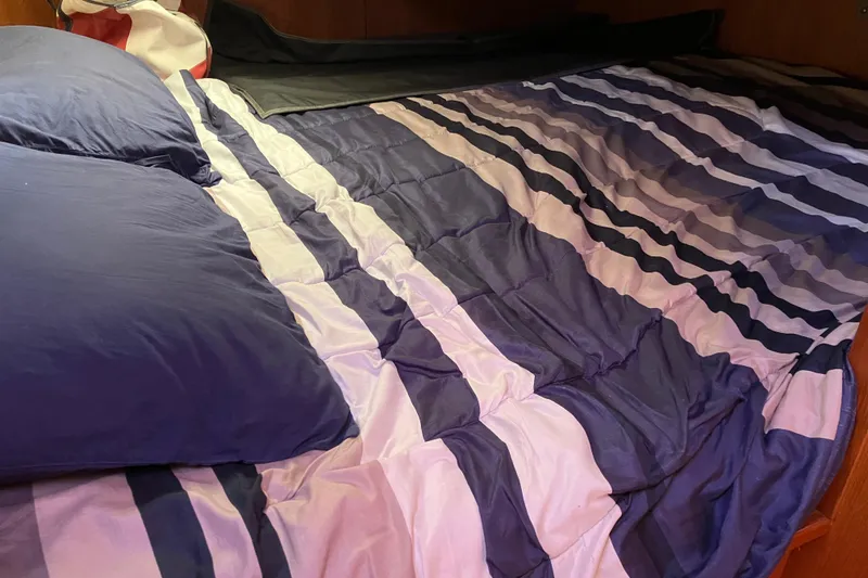 Slide: The Image of Cozy bed with striped bedding inside a 2005 Hunter 36 sailboat cabin. - 44