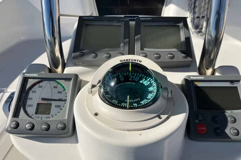 Slide: The Image of Cockpit instruments of a 2005 Hunter 36 sailboat, featuring Raymarine displays and a Danforth compass. - 54