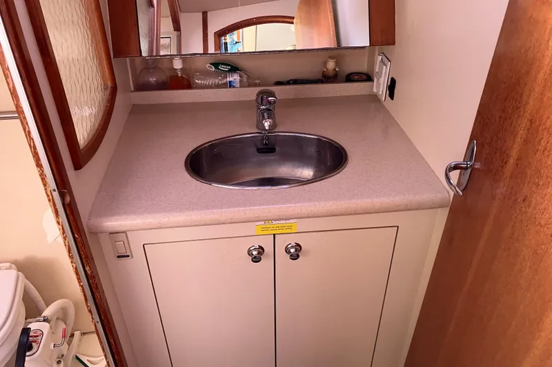 Slide: The Image of Compact bathroom sink area in a 2005 Hunter 36 yacht, featuring a mirror and storage cabinet. - 50