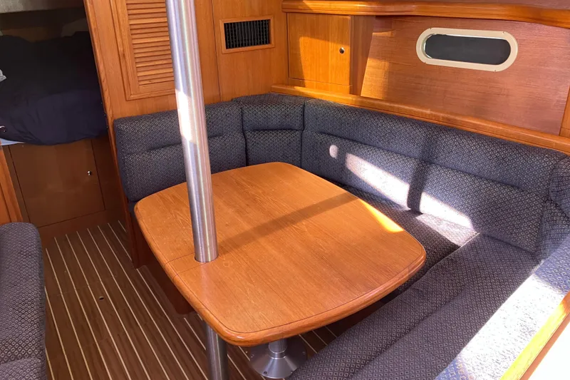 Slide: The Image of Cozy interior of a 2005 Hunter 36 sailboat with wooden table and cushioned seating. - 36