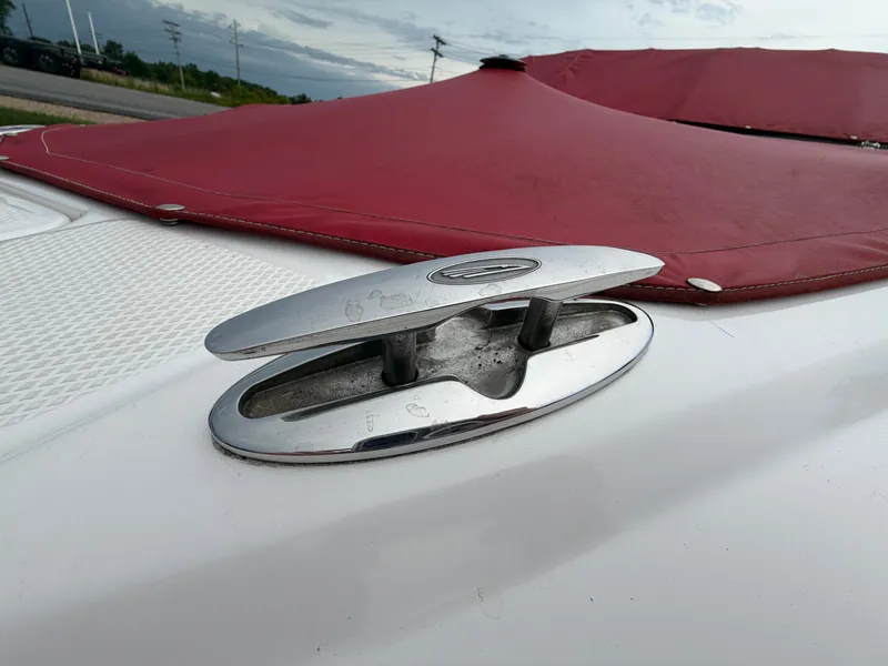 Slide: The Image of Close-up of a silver cleat on a white boat with a red cover. - 11