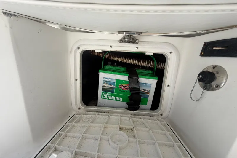 Slide: The Image of Marine battery compartment in a 2012 Glasstream 221 CC boat, featuring a secured cranking battery. - 56