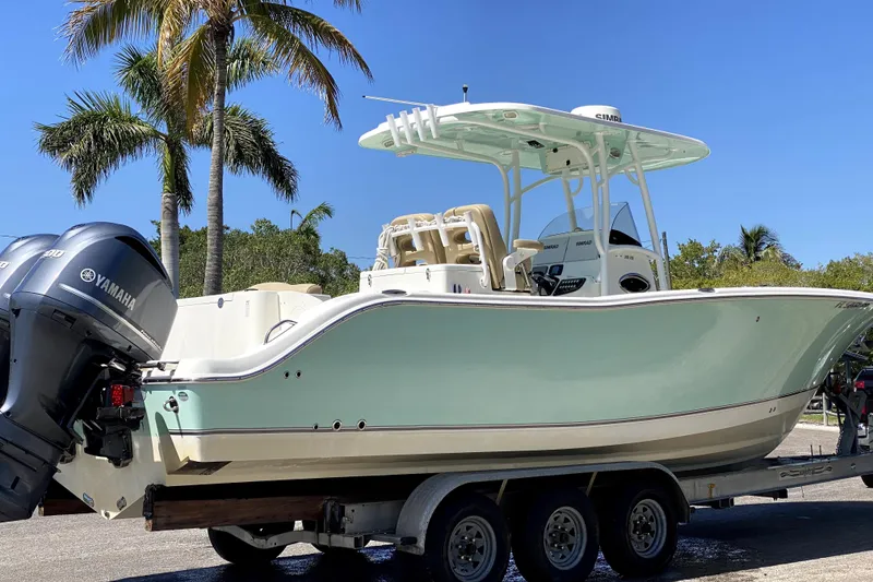 The Image of 2018 NauticStar 28 XS boat on trailer with Yamaha engines, palm trees in background. - 0