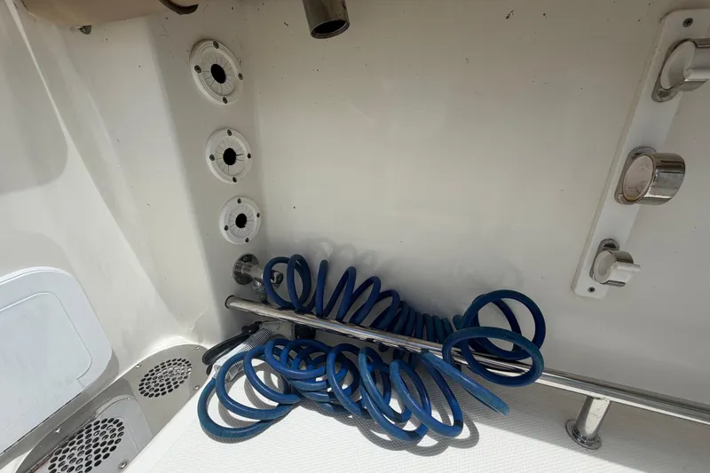 Slide: The Image of Coiled blue hose in 2018 NauticStar 28 XS boat compartment with drainage vents. - 71