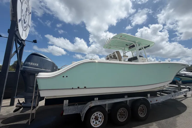 Slide: The Image of 2018 NauticStar 28 XS boat on trailer with Yamaha engine under cloudy sky. - 2