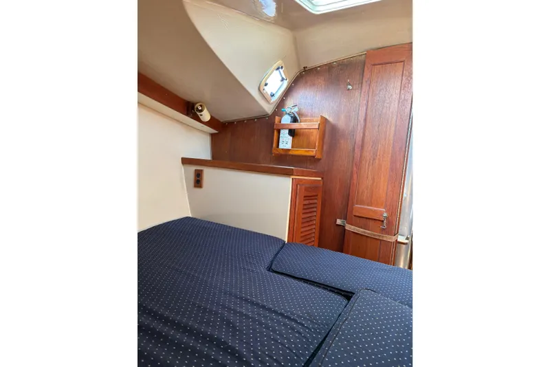 Slide: The Image of Interior cabin of a 1988 Catalina 34 sailboat with wooden accents and cozy bedding. - 10