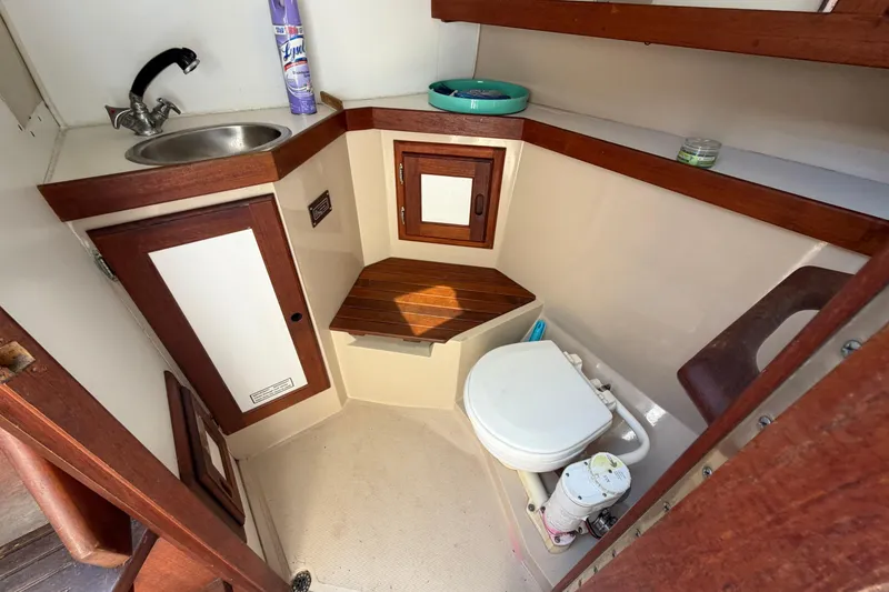 Slide: The Image of 1988 Catalina 34 boat bathroom with sink, toilet, and wooden cabinetry. - 11