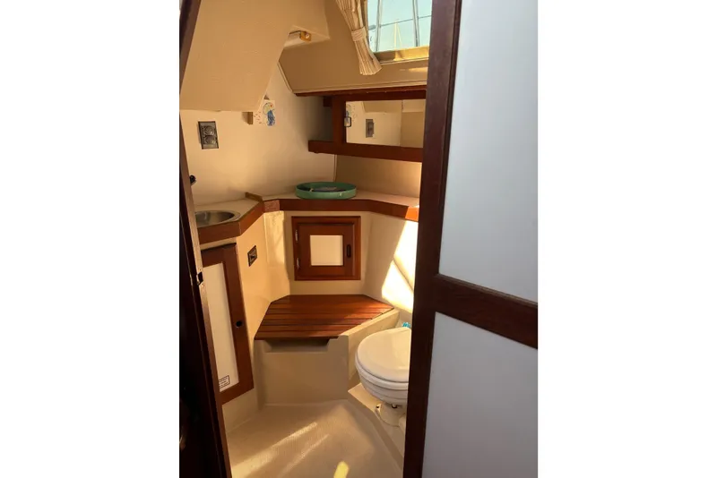 Slide: The Image of Interior of 1988 Catalina 34 sailboat bathroom with sink, toilet, and wooden accents. - 12
