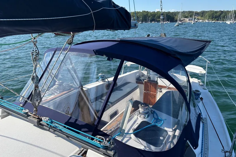 Slide: The Image of 1988 Catalina 34 sailboat with blue canopy, docked in a scenic marina. - 20