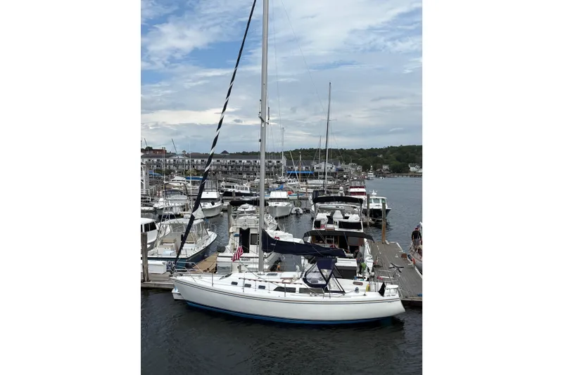 Slide: The Image of 1988 Catalina 34 sailboat docked in a marina with other boats under a cloudy sky. - 22