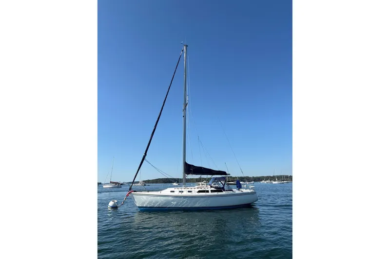 Slide: The Image of 1988 Catalina 34 sailboat anchored on calm water under clear blue sky. - 23