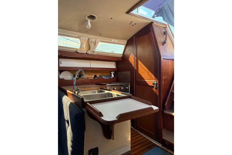 Slide: The Image of Interior of 1988 Catalina 34 sailboat galley with sink, stove, and wooden cabinetry. - 3