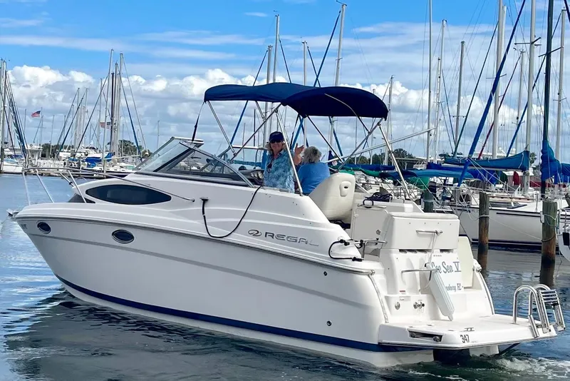 The Image of 2011 Regal 2565 Express Cruiser in marina, featuring sleek design and blue canopy. - 0
