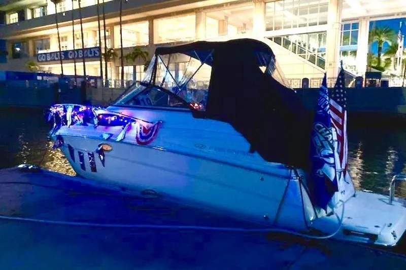 Slide: The Image of 2011 Regal 2565 Express Cruiser docked, decorated with lights and flags at night. - 1