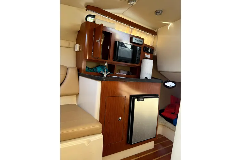 Slide: The Image of Interior of 2011 Regal 2565 Express Cruiser with kitchenette, featuring microwave and mini fridge. - 10