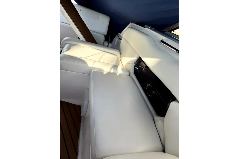 Slide: The Image of Interior seating of 2011 Regal 2565 Express Cruiser with white upholstery and wooden flooring. - 2