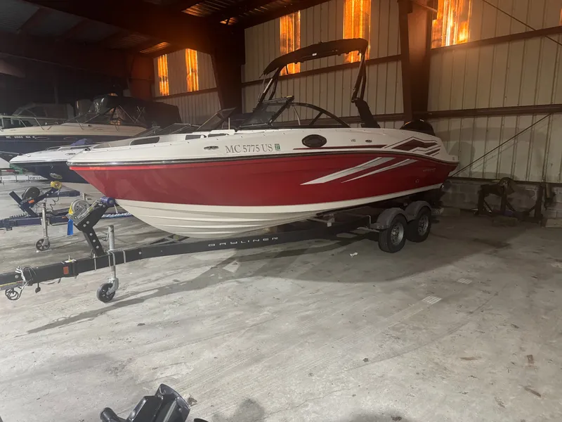 The Image of A red Bayliner VR6 boat from 2022 on a trailer inside a warehouse. - 0