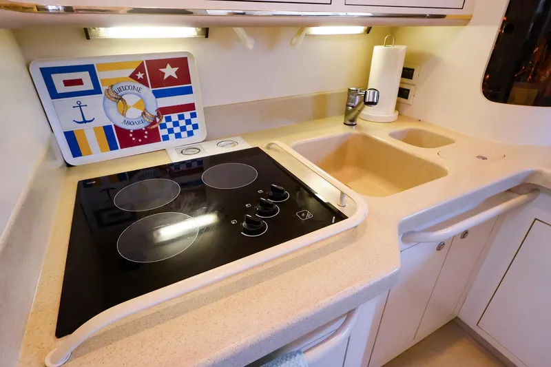 Slide: The Image of 1998 Sea Ray 500 Sundancer kitchen with electric stove, sink, and nautical decor. - 37