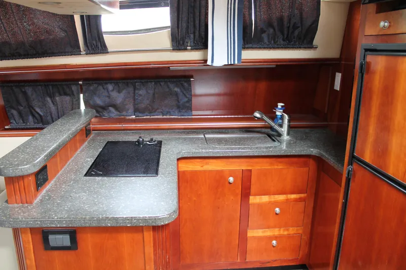 Slide: The Image of 2007 Cruisers Yachts 415 Express Motoryacht kitchen with wood cabinetry and modern appliances. - 22