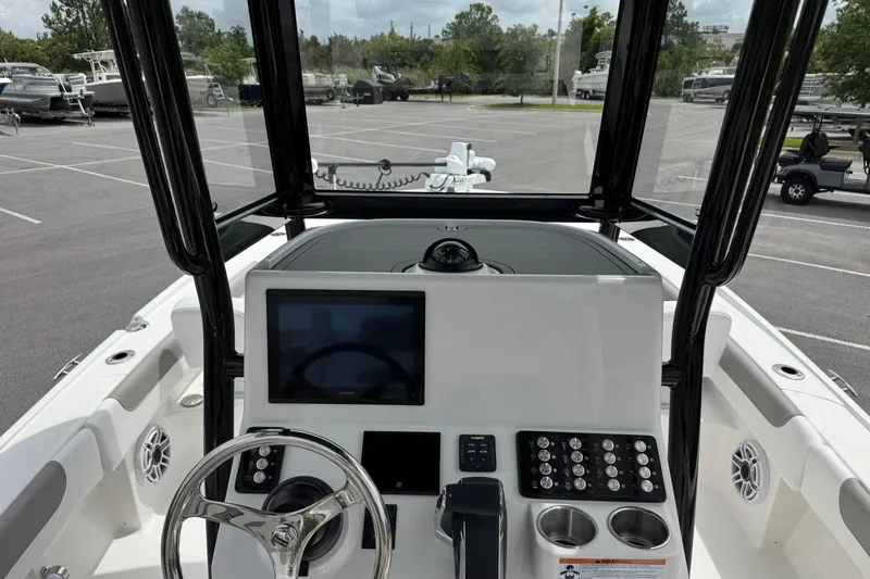 Slide: The Image of 2027 Caymas 26 HB boat dashboard with steering wheel, touchscreen, and control panel in a parking lot. - 20