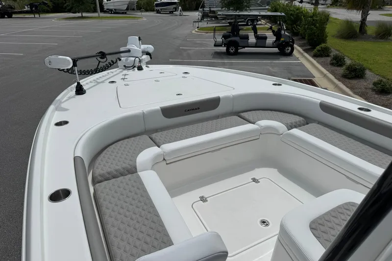 Slide: The Image of 2027 Caymas 26 HB boat interior with cushioned seating and modern design in a parking lot. - 24
