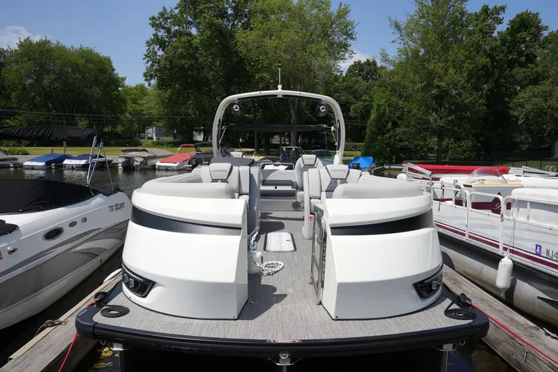 Slide: The Image of A sleek pontoon boat with modern seating and helm, surrounded by other boats at the dock. - 9