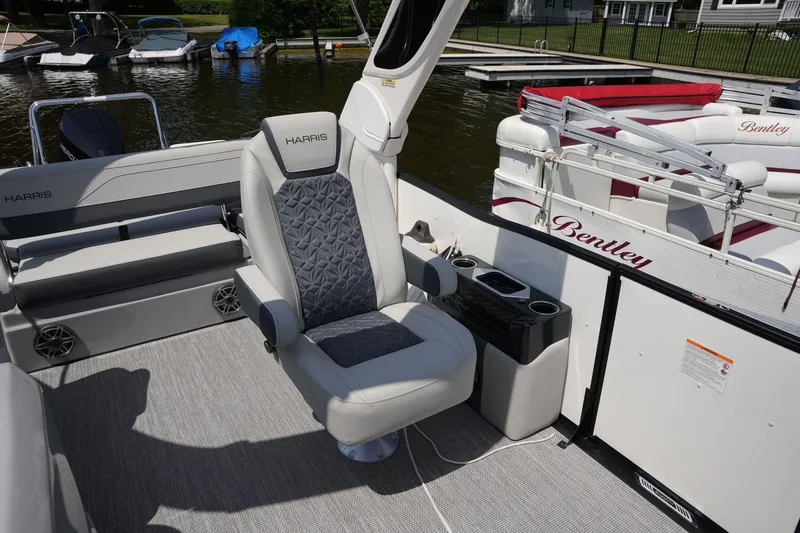 Slide: The Image of A modern pontoon boat seat with gray upholstery and armrests, surrounded by other boats at the dock. - 20