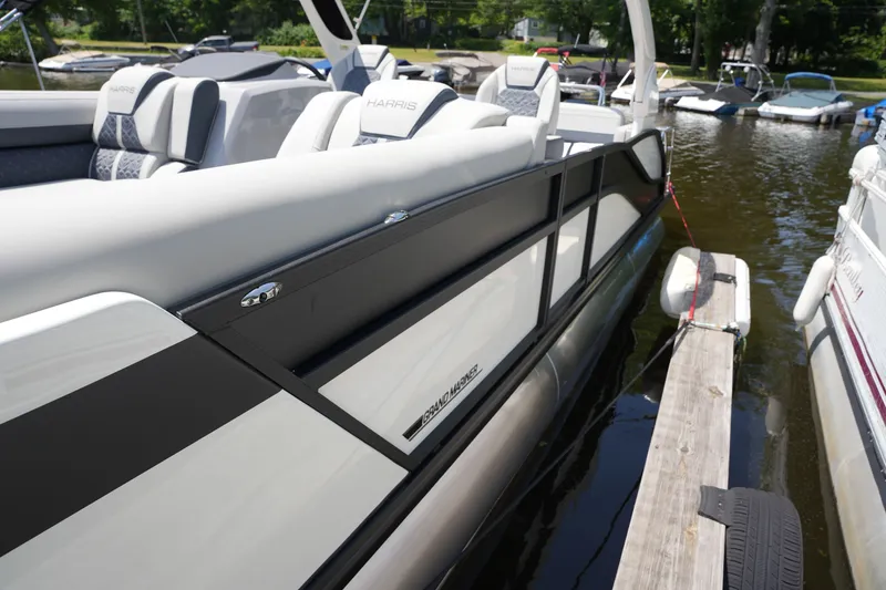 Slide: The Image of A sleek Harris 250GM pontoon boat docked at a wooden pier in calm waters. - 12